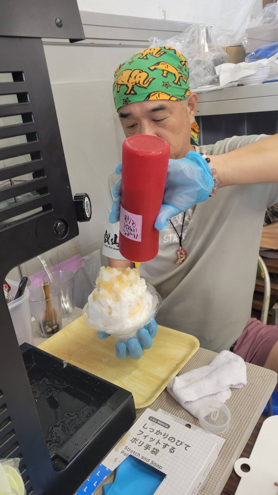 かき氷にシロップをかけて仕上げる出店者