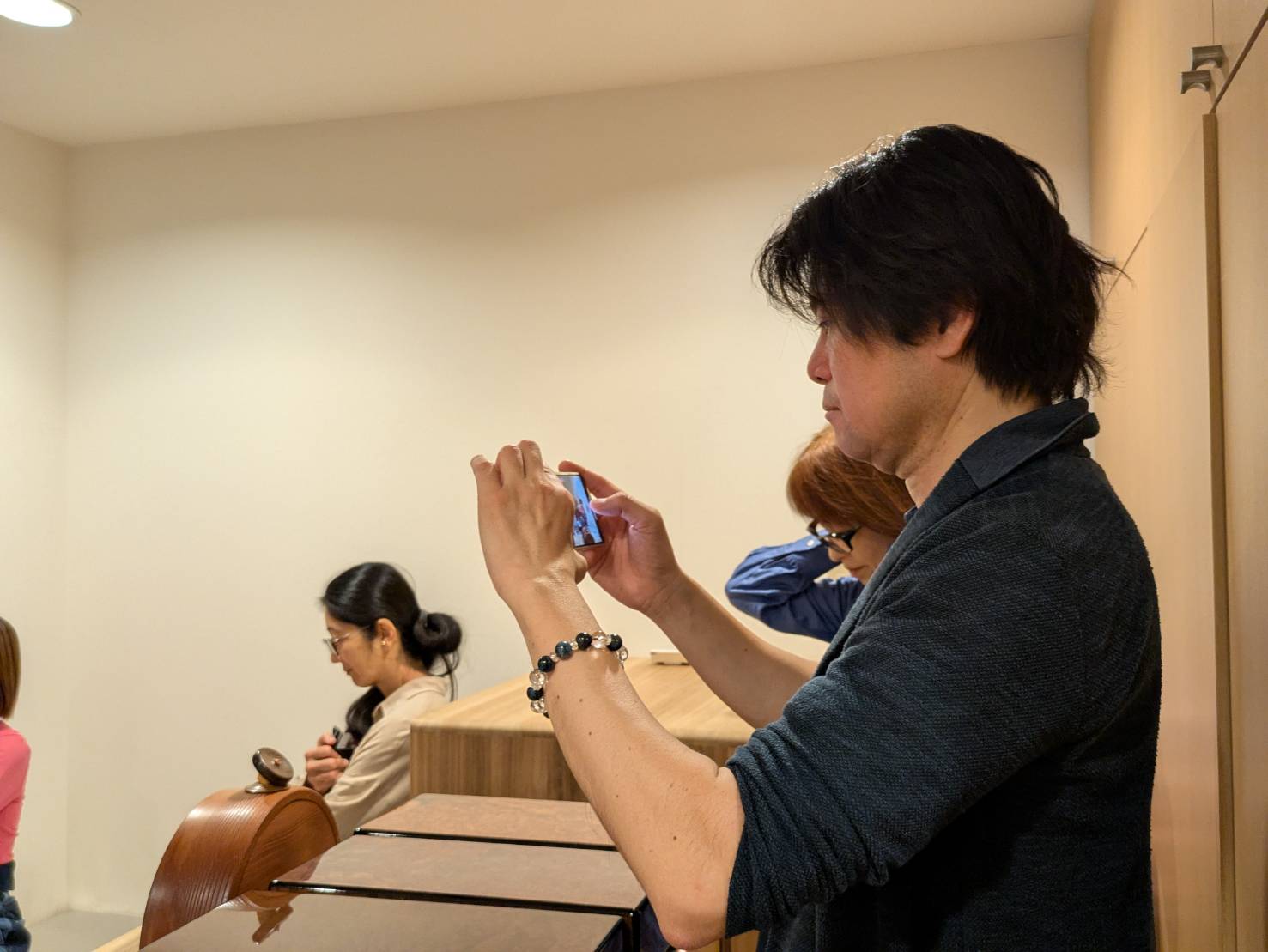 スマートフォンでオルゴール療法お披露目会を撮影する竹内誠一さん